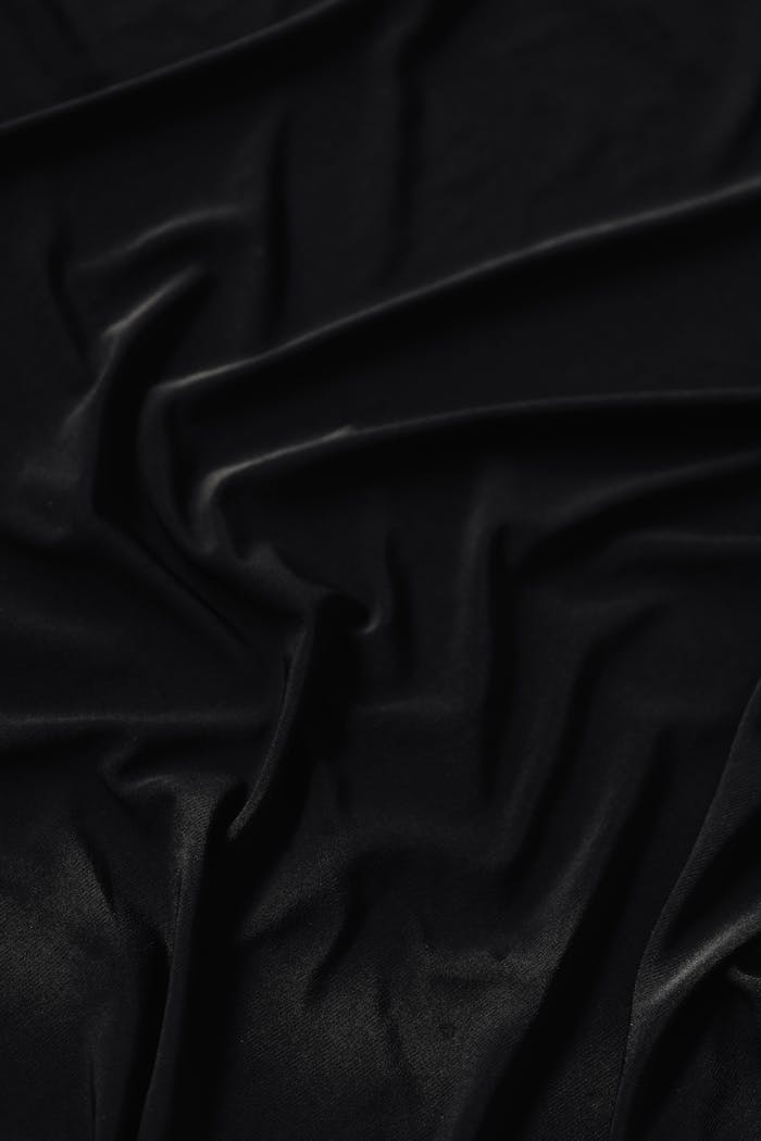 Close-up of elegant black fabric with intricate folds, perfect for design backgrounds.