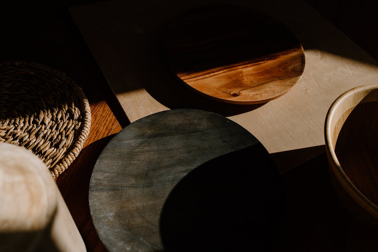 Artistic arrangement of wooden bowls showcasing shadows and texture in a minimalist setting.